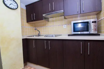 a kitchen with a microwave and a sink and a clock at estudio marina puerto sherry in El Puerto de Santa María