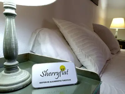 a sign on a glass table next to a bed at Sherryflat Mérito - Parking in Jerez de la Frontera