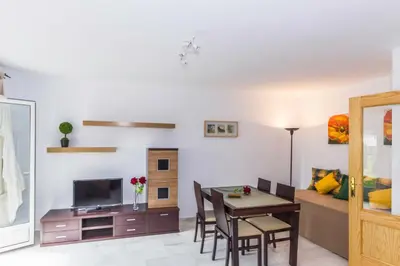 a living room with a dining room table and a television at Duplex Camino del Tejar in Conil de la Frontera