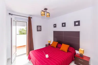 a bedroom with a large red bed with orange pillows at Duplex Camino del Tejar in Conil de la Frontera