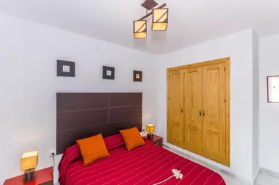 a bedroom with a large red bed with orange pillows at Duplex Camino del Tejar in Conil de la Frontera