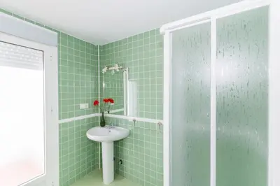 a green tiled bathroom with a sink and a shower at Duplex Camino del Tejar in Conil de la Frontera