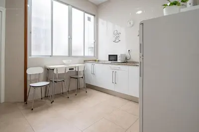 a kitchen with white cabinets and a table and stools at Apartamento Casa Senorial Cadiz in Cádiz