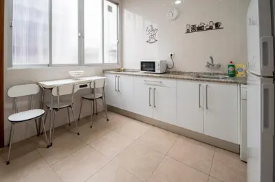 a kitchen with white cabinets and a sink and a table at Apartamento Casa Senorial Cadiz in Cádiz