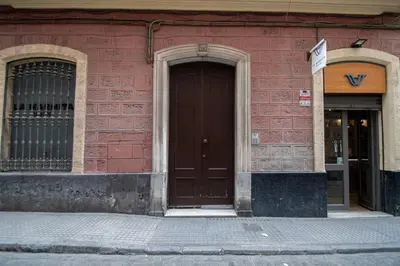 a red brick building with a brown door and two windows at Apartamento Casa Senorial Cadiz in Cádiz