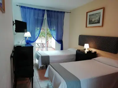 a hotel room with two beds and a window at Hostal Alhaja Playa in El Puerto de Santa María