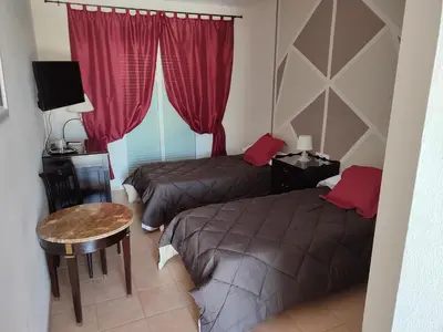 a bedroom with two beds and a table and a window at Hostal Alhaja Playa in El Puerto de Santa María
