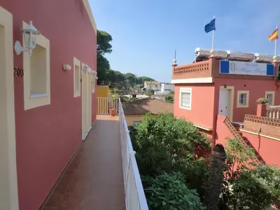 a balcony of a pink building with a white fence at Hostal Alhaja Playa in El Puerto de Santa María