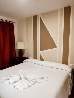 a bedroom with a white bed with a bow on it at Hostal Alhaja Playa in El Puerto de Santa María