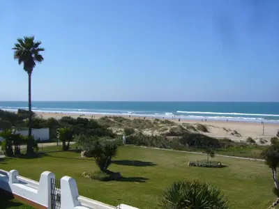 a view of a beach with a white fence and the ocean at Casa Sargo in Chiclana de la Frontera