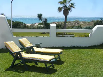 two chairs sitting in the grass near the ocean at Casa Sargo in Chiclana de la Frontera