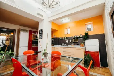 a kitchen with a glass table and orange chairs at Loft del Arte in Cádiz