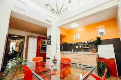 a kitchen with a glass table and orange chairs at Loft del Arte in Cádiz