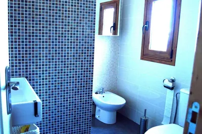 a blue tiled bathroom with a toilet and a sink at Apartamento El Mirador de Cadiz in Cádiz