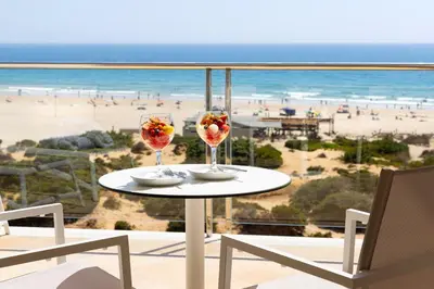a bedroom with a bed and a living room at Hipotels Barrosa Palace & Spa in Chiclana de la Frontera