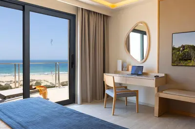 a woman standing on a balcony overlooking the beach at Hipotels Barrosa Palace & Spa in Chiclana de la Frontera