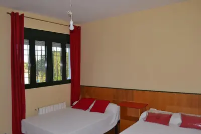 two beds in a room with red curtains at Villa las Redes in El Puerto de Santa María