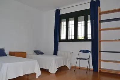 a room with two beds and a chair and a window at Villa las Redes in El Puerto de Santa María