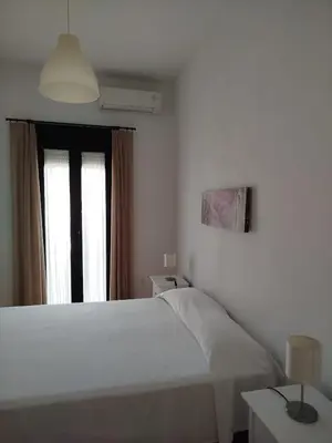 a white bedroom with a bed and a window at Apartamentos Fariñas 11 in Sanlúcar de Barrameda