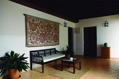 a living room with a bench and a tapestry on the wall at Apartamentos Fariñas 11 in Sanlúcar de Barrameda
