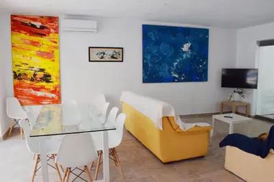 a living room with a table and chairs and paintings at Sancti Petri House in Chiclana de la Frontera