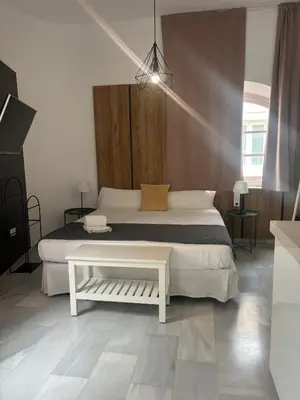a bedroom with a white bed and a table at ISA Cádiz in Cádiz
