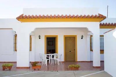 a white house with a yellow door and a table and chairs at Villa Juan in Conil de la Frontera