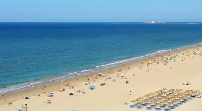 a group of people on a beach with umbrellas at Hidden Gem Playa Helios con Ascensor & Parking in Cádiz