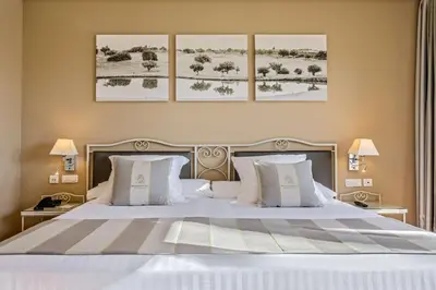 a bedroom with a large white bed with three pictures on the wall at Barceló Jerez Montecastillo & Convention Center in Jerez de la Frontera