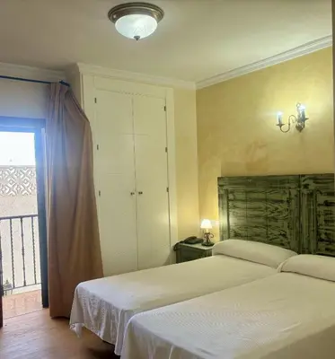 a bedroom with two white beds and a window at Hotel Chipiona in Chipiona