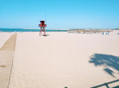 a beach with a lifeguard tower on the beach at VillaLaJaraCom CHALET CON PISCINA, PROHIBIDAS DESPEDIDAS GRUPOS Y FIESTAS, SOLO FAMILIAS RECEPCION POR EL PROPlETARIO in El Puerto de Santa María