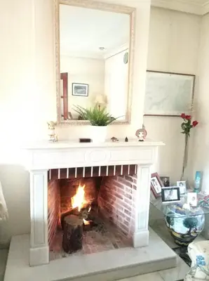 a fireplace with a mirror and a fire place at VillaLaJaraCom CHALET CON PISCINA, PROHIBIDAS DESPEDIDAS GRUPOS Y FIESTAS, SOLO FAMILIAS RECEPCION POR EL PROPlETARIO in El Puerto de Santa María