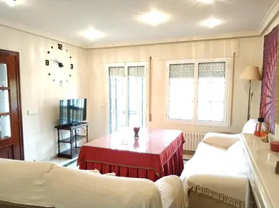 a living room with two beds and a red table at VillaLaJaraCom CHALET CON PISCINA, PROHIBIDAS DESPEDIDAS GRUPOS Y FIESTAS, SOLO FAMILIAS RECEPCION POR EL PROPlETARIO in El Puerto de Santa María