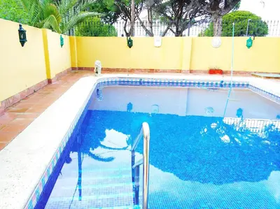 a swimming pool with blue water in a yellow wall at VillaLaJaraCom CHALET CON PISCINA, PROHIBIDAS DESPEDIDAS GRUPOS Y FIESTAS, SOLO FAMILIAS RECEPCION POR EL PROPlETARIO in El Puerto de Santa María