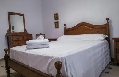a bedroom with a bed with white sheets and a mirror at Roche Pinos Verdes in Roche