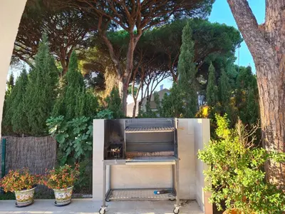 an outdoor grill in a garden with trees and plants at Roche Pinos Verdes in Roche