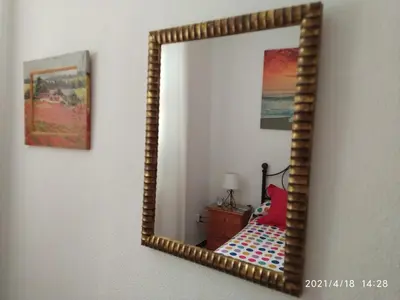 a mirror on a wall with a bed in a room at Los Tres Girasoles in Cádiz