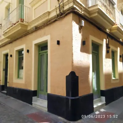 a building with green doors on a street at Los Tres Girasoles in Cádiz