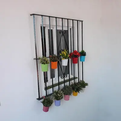 a black fence with plants in colorful pots on it at Atico Soleado in Cádiz