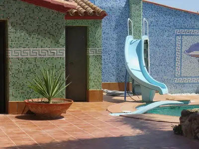 a swimming pool with a slide next to a building at HIGOS CHUMBOS, CASA RURAL COMPARTIDO in Chiclana de la Frontera