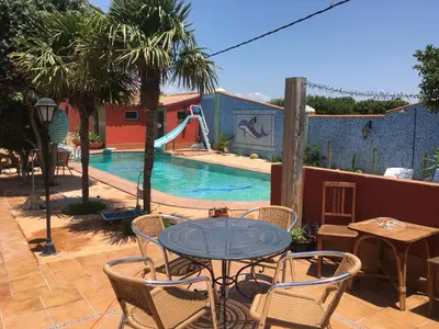 a patio with a table and chairs next to a pool at HIGOS CHUMBOS, CASA RURAL COMPARTIDO in Chiclana de la Frontera