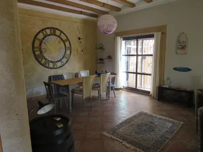 a dining room with a table and chairs and a large clock at HIGOS CHUMBOS, CASA RURAL COMPARTIDO in Chiclana de la Frontera