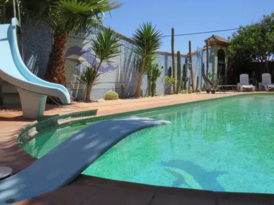 a slide in a swimming pool with palm trees at HIGOS CHUMBOS, CASA RURAL COMPARTIDO in Chiclana de la Frontera