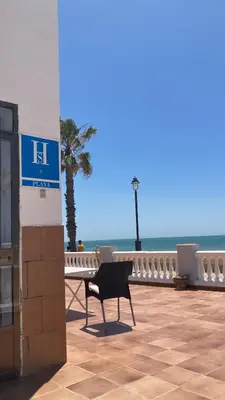 a chair sitting on a patio next to the ocean at Tranvía Beach House in Chipiona