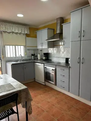 a kitchen with stainless steel appliances and a table at La Casa del Camaleon in Chipiona