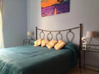 a bedroom with a green bed with four pillows at Apartamentos Doñana in Sanlúcar de Barrameda