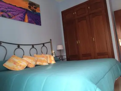 a bedroom with a blue bed with four pillows at Apartamentos Doñana in Sanlúcar de Barrameda