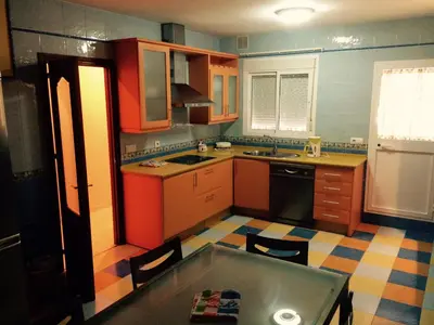 a kitchen with orange and blue cabinets and a table at Apartamentos Doñana in Sanlúcar de Barrameda