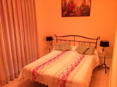 a bedroom with a bed with orange walls and two lamps at Apartamentos Doñana in Sanlúcar de Barrameda
