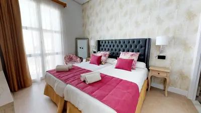 a large bedroom with a large bed with pink pillows at Hostal Boutique La Española in Rota